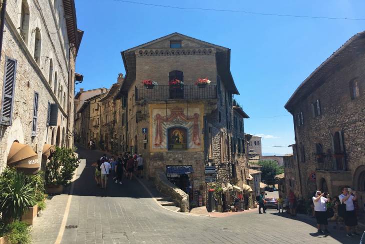 Een straatje in Assisi Umbrie Italie met in het midden een winkel met prachtige muurschildering.